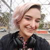 Nic with pink hair looking happy and confident. They're standing next to a colourful UooUoo sculpture outside Melbourne Museum